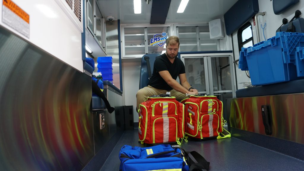 Man stocking supplies in mobile ambulance simulator.